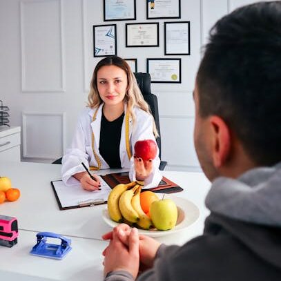 A nutritionist advises a client about healthy eating in a modern office with fruits.
